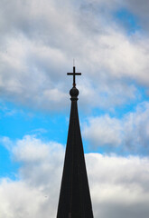 Top roof of the cathedral with a crucifix. Gothic roof and the christ cross on the top against blue sky.
