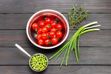 Tomatoes in metal bowl. Green onions, green peas and thyme sprigs.