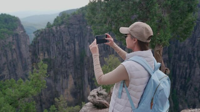A girl takes pictures on her phone of the landscape of the canyon of Taza. Tazy Canyon in Turkey. Beautiful mountain landscapeA girl takes pictures on her phone of the landscape of the canyon of Taza.