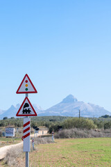 Caution signs for passing trains and traffic lights on a country road