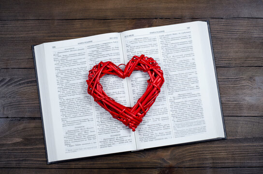 Open book, Bible. On the table. Red heart. The concept of love for God and Scripture.