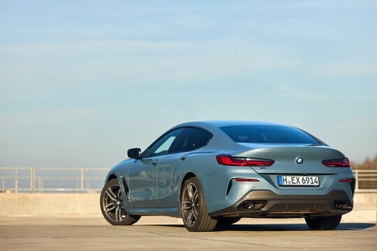 Berlin - October 2021: BMW 8 Series G16 Gran Coupe 840i xDrive M-pack 2021. Left side three quarter back view selective focus over urban background under blue sky at seashore promenade with copyspace.