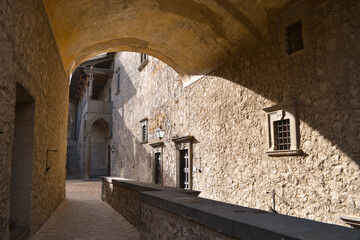 An aisle of an ancient castle in a sunny day, Italy. Old walls and arches made of stone