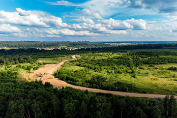 Panoramic view from a height of a country road in the middle of the countryside. Country and city buildings in the background