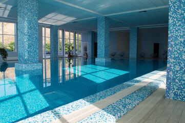 Traditional indoor water pool with large windows reflecting on the surface of the water. Selective focus. Copy space