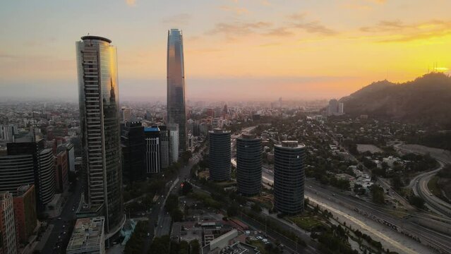 Aerial pan left of San Cristobal Hill and modern skyscrapers in Sanhattan area at sunset, Santiago, Chile