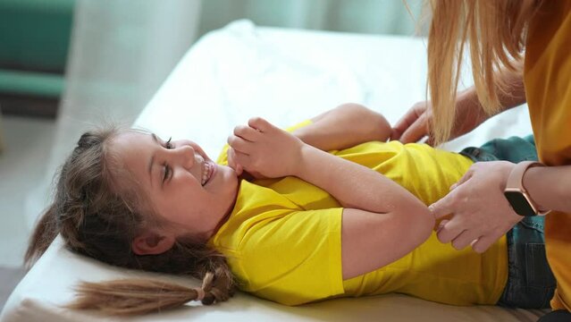 mother tickle daughter. happy family a playing on the bed at home. happy family home kid dream concept. mom tickles daughter play lifestyle laugh fun. mom tickle daughter lying on the bed