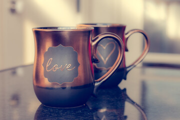 Love and heart coffee tea mugs, romantic Valentines card backdrop in brown chocolate tones at sunset