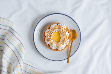 Lemon tart decorated with wiped cream. Decorated with flowers and different cloths and golden spoon. Lemon custard cream and sweet dough.