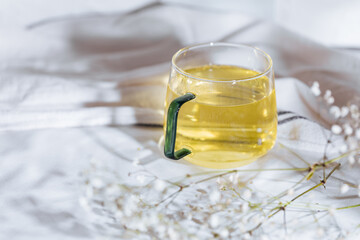 Cup of chamomile tea in transparent mug served with slice of lemon and orange. Tea break. 