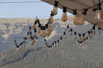 garlands of decorative large light bulbs against the backdrop of mountains