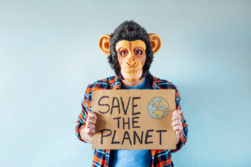 Man with monkey mask showing a sign that says SAVE THE PLANET.