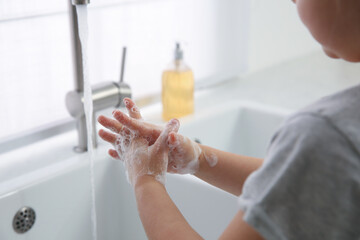 Obraz na płótnie Canvas Little girl washing hands with liquid soap at home, closeup