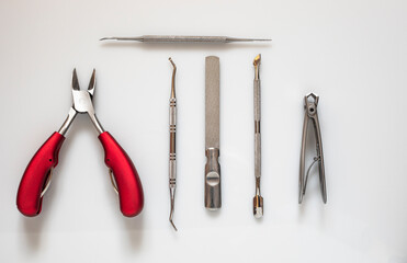 podiatry utensils on a bright white background clippers with red handles collection of items lay flat from above
