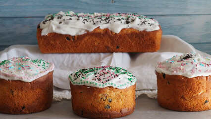 Rustic baking of non-traditional Easter cakes for orthodox Easter. Cupcakes with white icing and colored sprinkles on a blue wood background. Romantic wedding national dessert