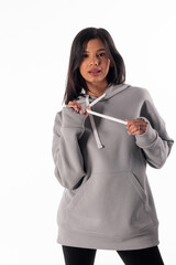 Fototapeta premium An attractive woman of Latin appearance wears a gray hoodie against a white background. The girl looks sexy and happy. The elegant brunette is wearing a light gray sweatshirt. All-season clothing