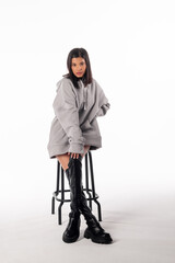 Fototapeta premium An attractive woman of Latin appearance wears a gray hoodie against a white background. The girl looks sexy and happy. The elegant brunette is wearing a light gray sweatshirt. All-season clothing