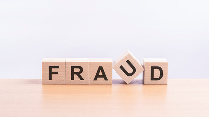 fraud - words from wooden blocks with letters, of inform brief concept, light yellow background