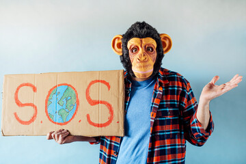 Man with monkey mask showing a sign that says S.O.S.