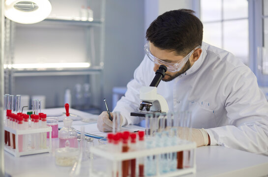Focused male young Caucasian assistant or technician work with test tube glass do research in lab. Man scientist or tester make experiments or chemistry investigation. Biotechnology, science concept.