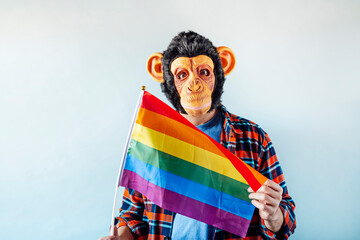 Man in monkey mask holding gay flag.