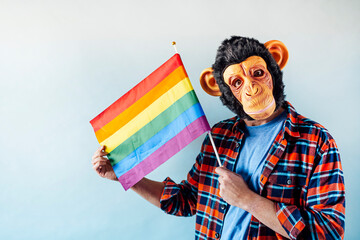 Man in monkey mask holding gay flag.