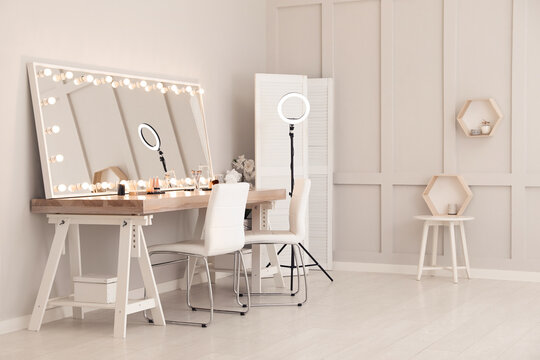 Modern mirror with light bulbs on dressing table in makeup room
