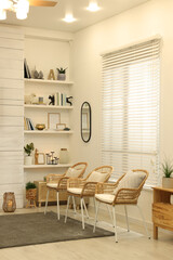 Armchairs near shelves with different decor in room. Interior design