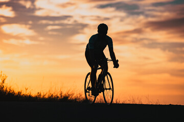 Obraz premium cyclist silhouette at sunset sports and fitness concept