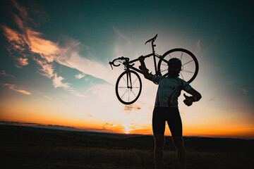cyclist silhoutte with bicycle raised to sky race and victory concept