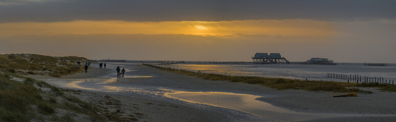 Walking on the North sea coast in winter. Winter beach walk. Panorama view of the Wadden sea at Sankt Peter Ording with stilt houses in winter, North Sea, North Friesland, Schleswig-Holstein, Germany.