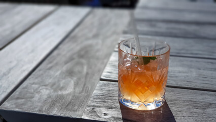 alcoholic cocktail and drink in a glass on a ragged wooden table in the sun