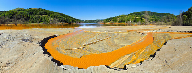 Mountain lake landscape - liquid residues from a gold mine discharged into a lake, pollution