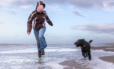 girl and dog running on the beach