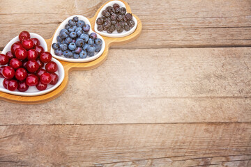 Portion wooden dish on light wooden background top view. Wooden partitioned dish divided into equal 3 section with berries.Compartmentals dish for food, dessert, fruit, berries and vegetable.
