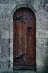 Vintage, old wooden door in Celtic or Gothic style with iron hinge and frame ornaments in mausoleum, Glasnevin Cemetery, Dublin, Ireland