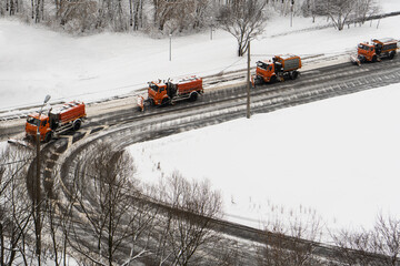 Group of red snowplows clean the snow on the road after winter snowfall.