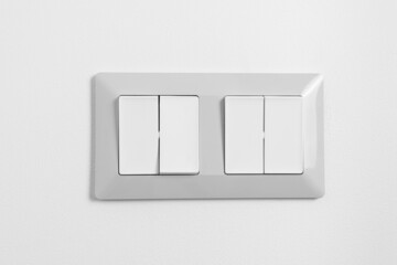 Light switch with four buttons on white wall at home. One button switch on. Power, electricity, environmental conservation, energy saving concept.