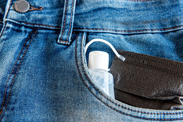 Mask and alcohol gel in jeans pocket, COVID-19 prevention.