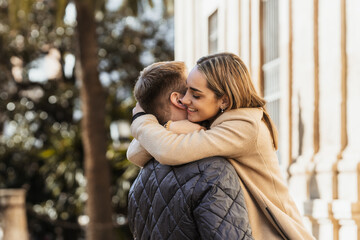 Fototapeta premium a smiling young woman hugs her boyfriend intensely
