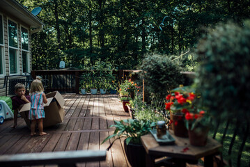 View of porch with boy and girl playing in box surrounded by plants