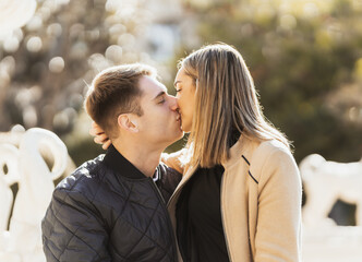 Fototapeta premium young woman kisses her boyfriend while sitting on his lap