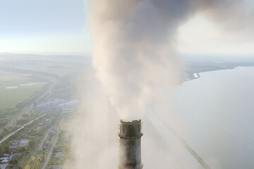 Aerial view of coal power plant high pipes with black smoke moving up polluting atmosphere at sunrise.