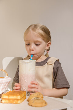 Cute little girl eating cookies with milkshake