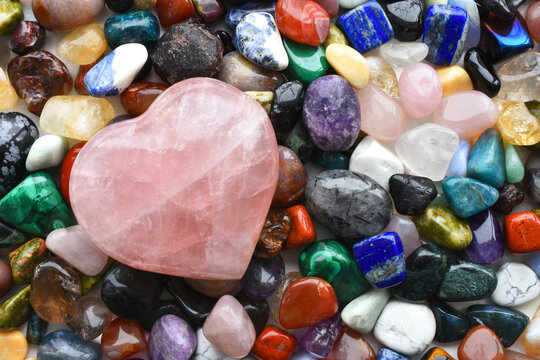 A top view image of a large variety of healing crystals with a large rose quartz crystal heart. 