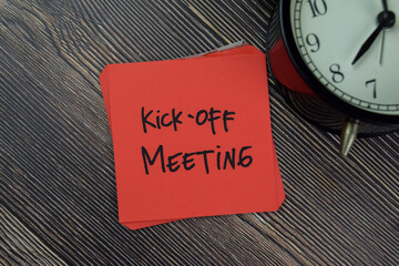 Kick-off Meeting write on sticky notes isolated on Wooden Table.
