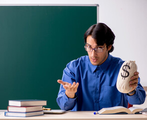 The young male teacher in front of chalkboard