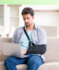 Young student man with hand injury sitting on the sofa