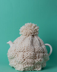 white teapot with a knitted tea cosy