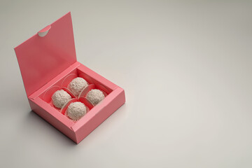 Delicious candies in pink box on light grey background, space for text